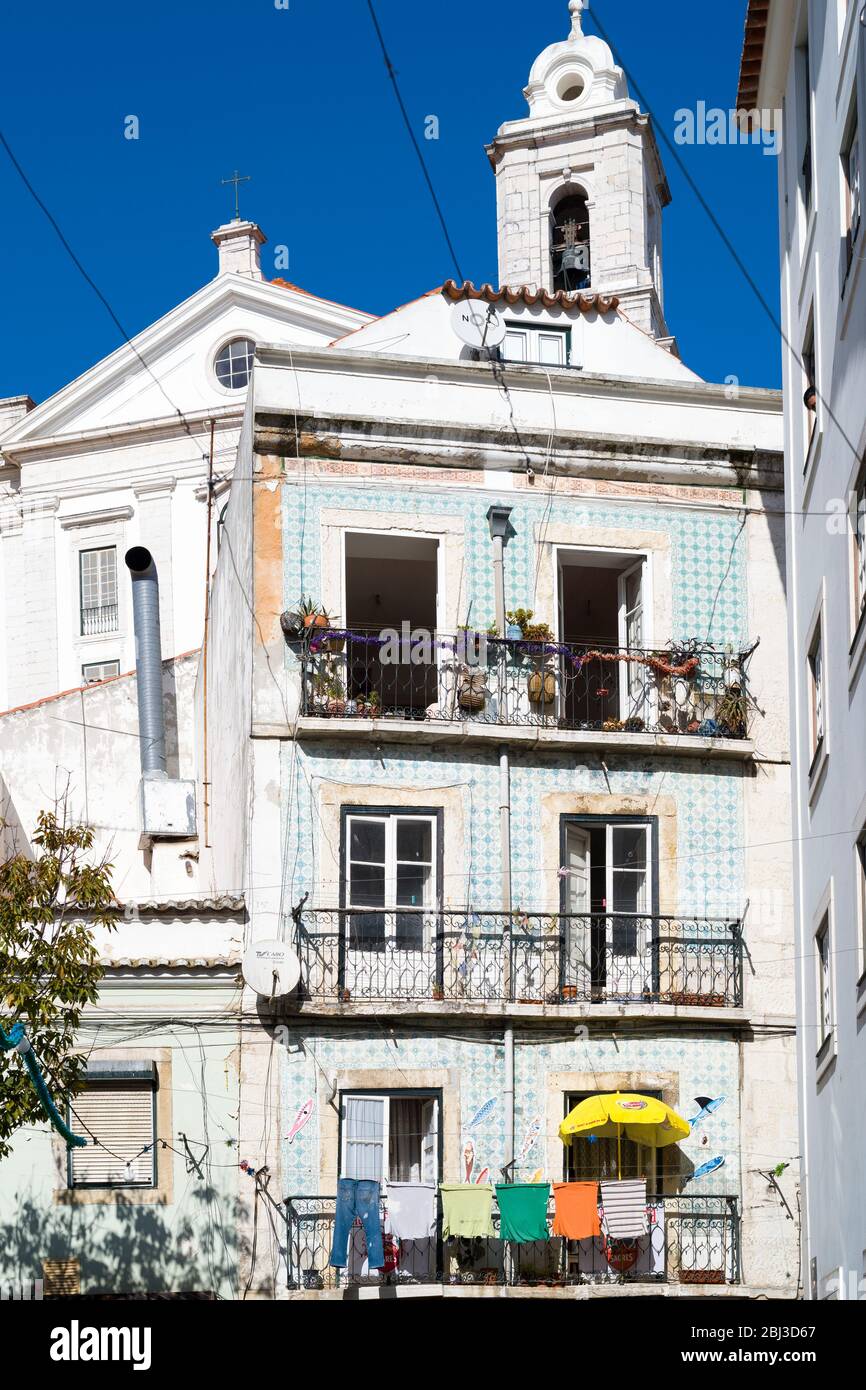 Typical Portugese street scene with laundry hanging out to dry on washing lines on balcony in Lisbon, Portugal Stock Photo