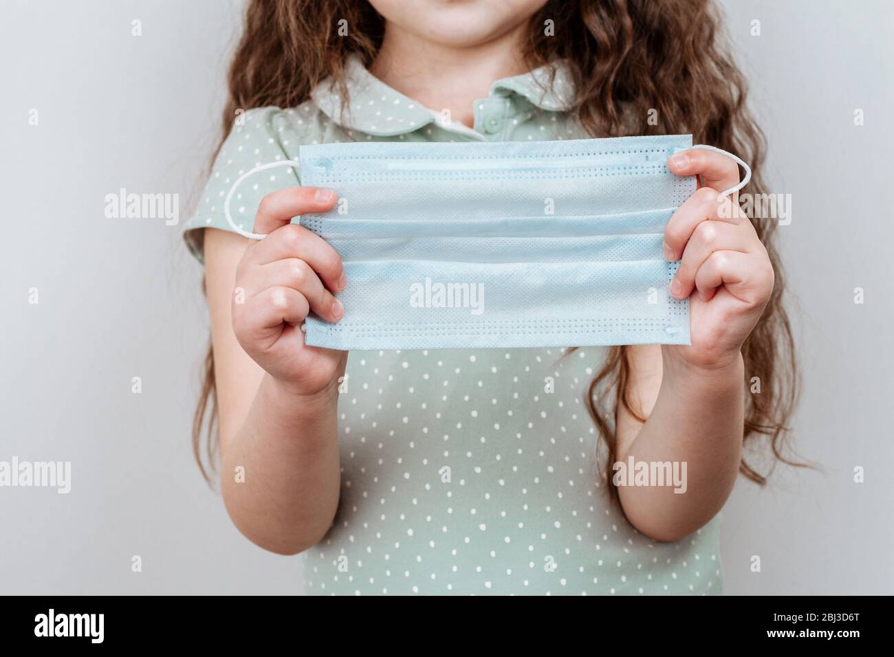A Girl holds a medical masks in her hands. Antiviral medical mask for protection against influenza. Stock Photo