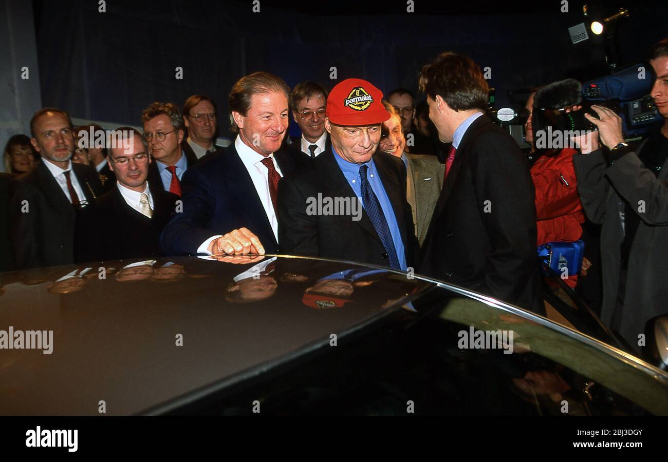 Niki Lauda ( In red hat) and Wolfgang Reitzle looking at the car at the new 2001 Press launch of the Aston Martin Vanquish in Geneva. Stock Photo