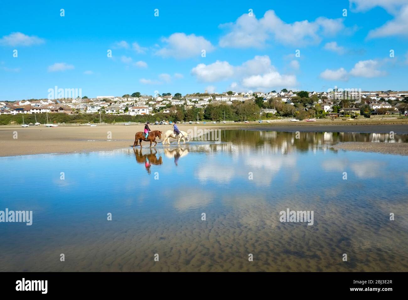 Pony trekking on the Gannel Estuary at low tide in Newquay in Cornwall. Stock Photo