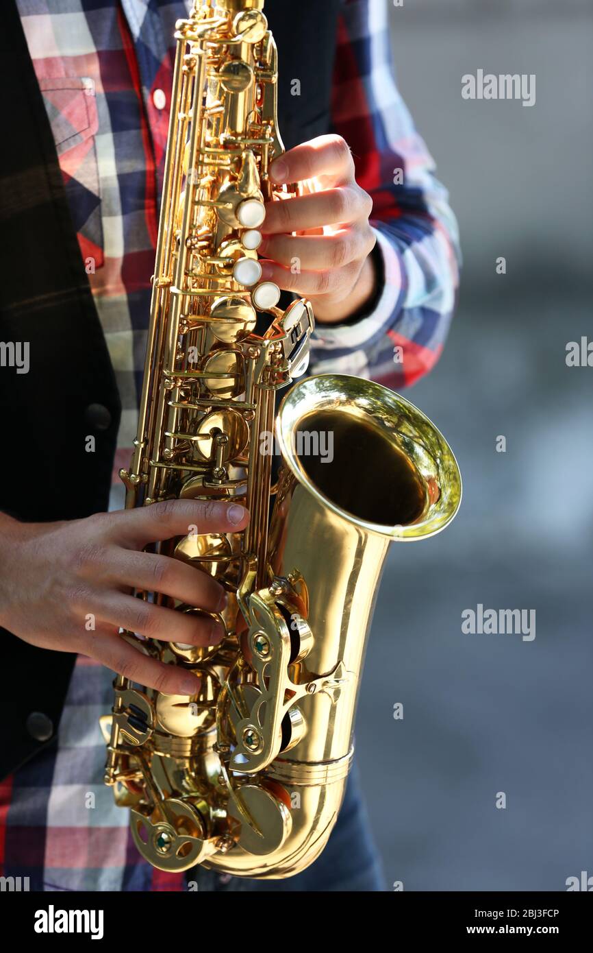 Handsome young man plays sax outdoors, close up Stock Photo - Alamy