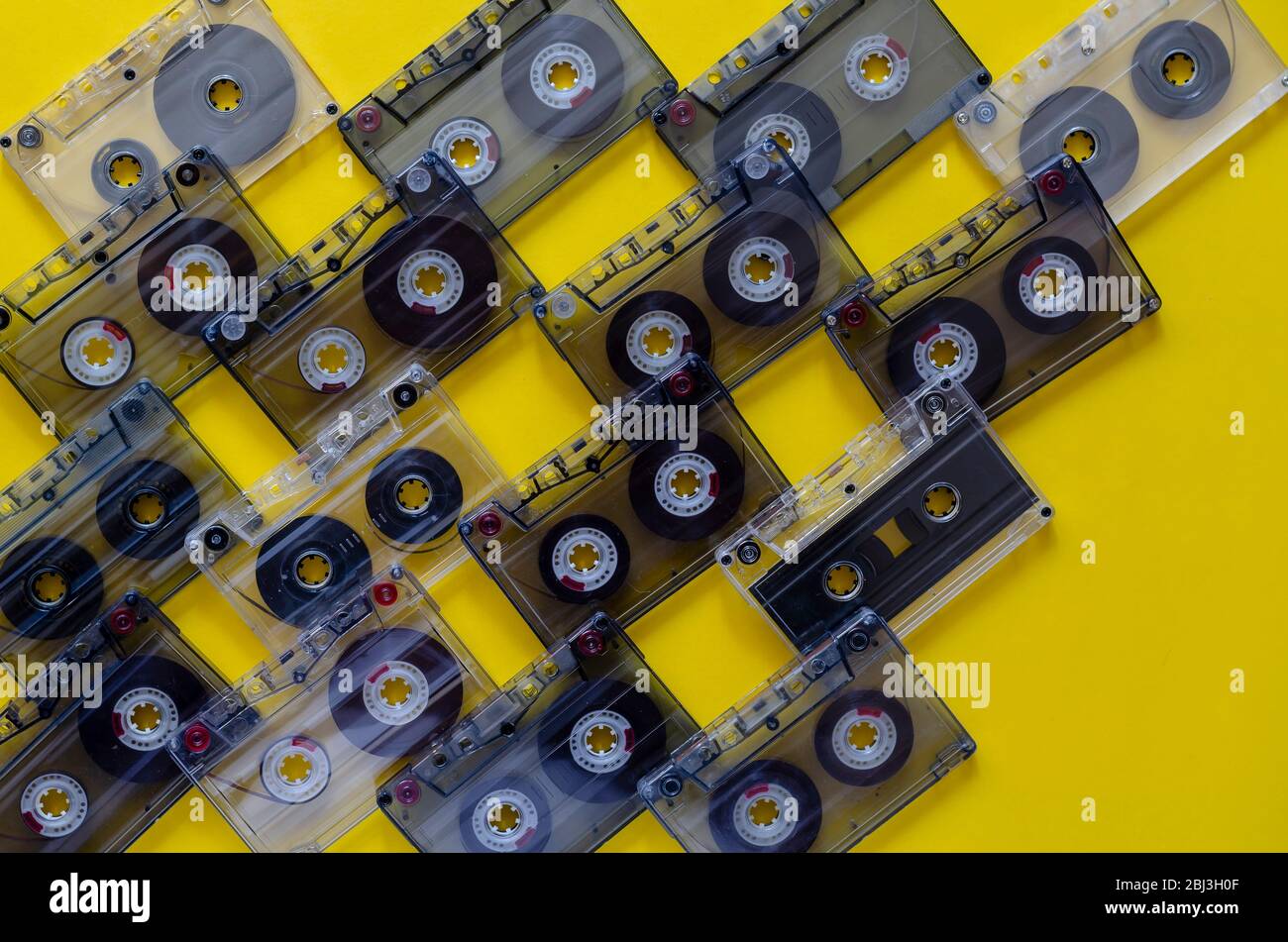 Vintage audio cassettes on a yellow background. 80s music on audio cassettes. Many audio tapes