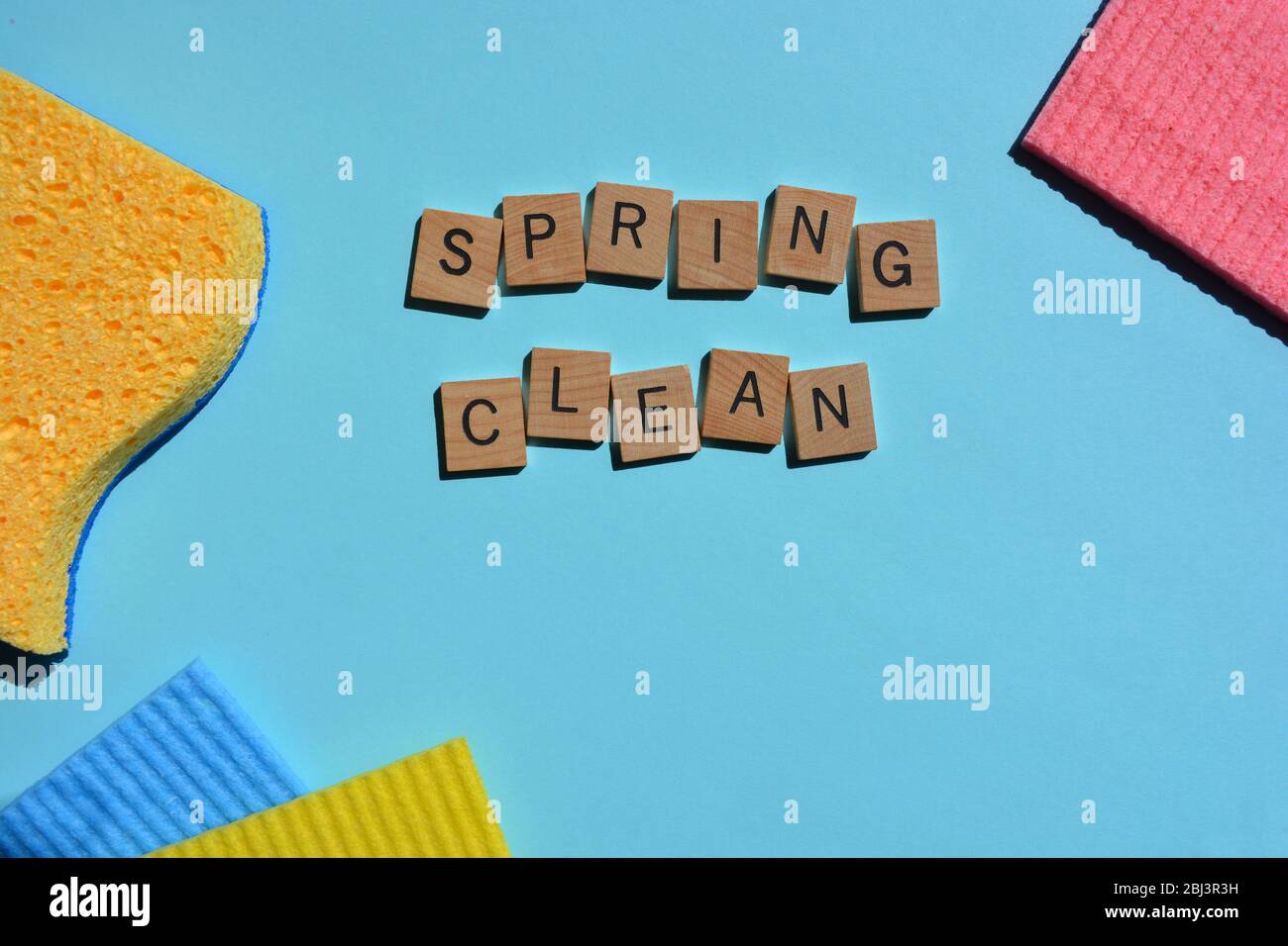Spring Clean, words in alphabet letters with colorful sponges on blue background with copy space Stock Photo