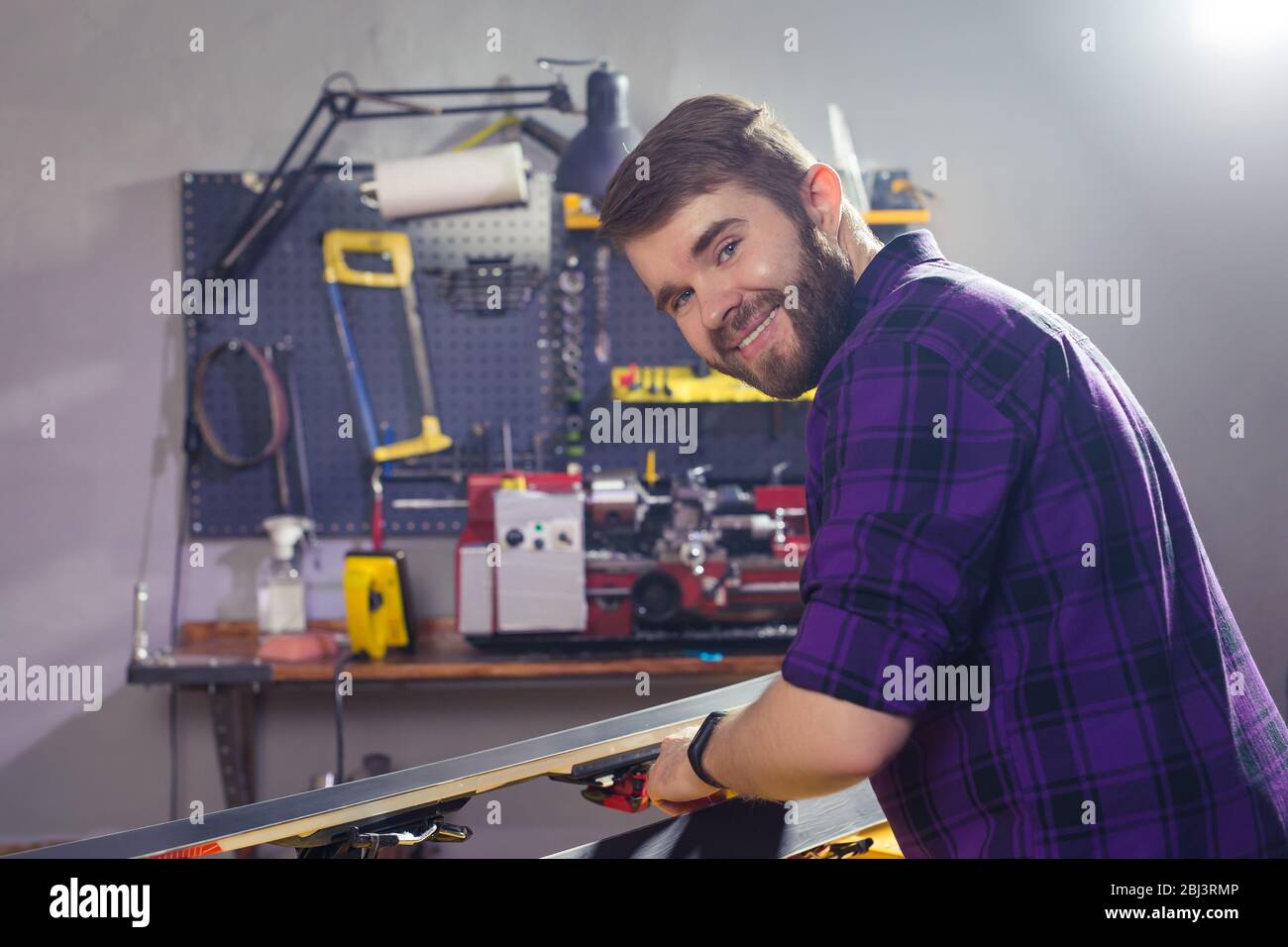 Repair, service and people concept - a man repairing the ski by rubbing a paraffin Stock Photo