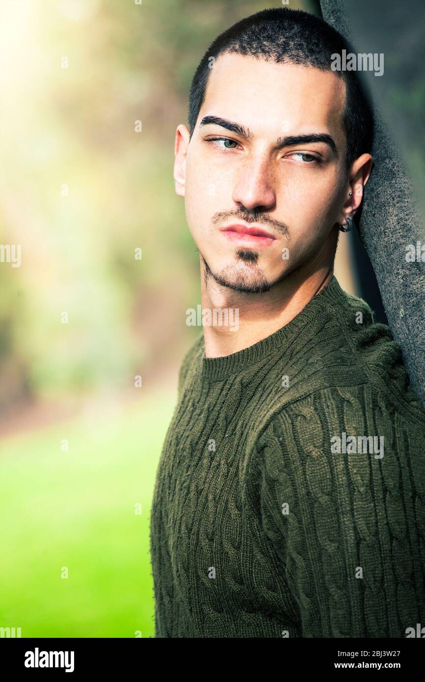 Beautiful and young man leaning with his back on a tree. Natural background  in a park. Thoughtful and relaxed attitude. The male has short hairstyle a  Stock Photo - Alamy