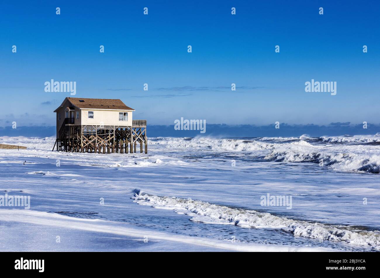 Nags Head beach house on stilts surrounded by high tide storm surf. Stock Photo