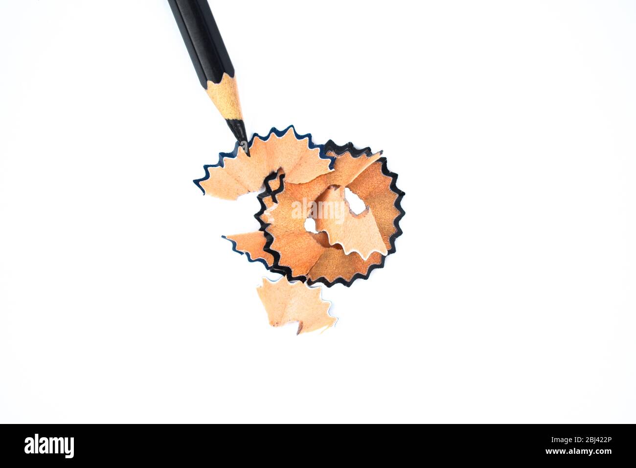 A black color wood pencil crayons pointing at some brown color pencil shavings Stock Photo