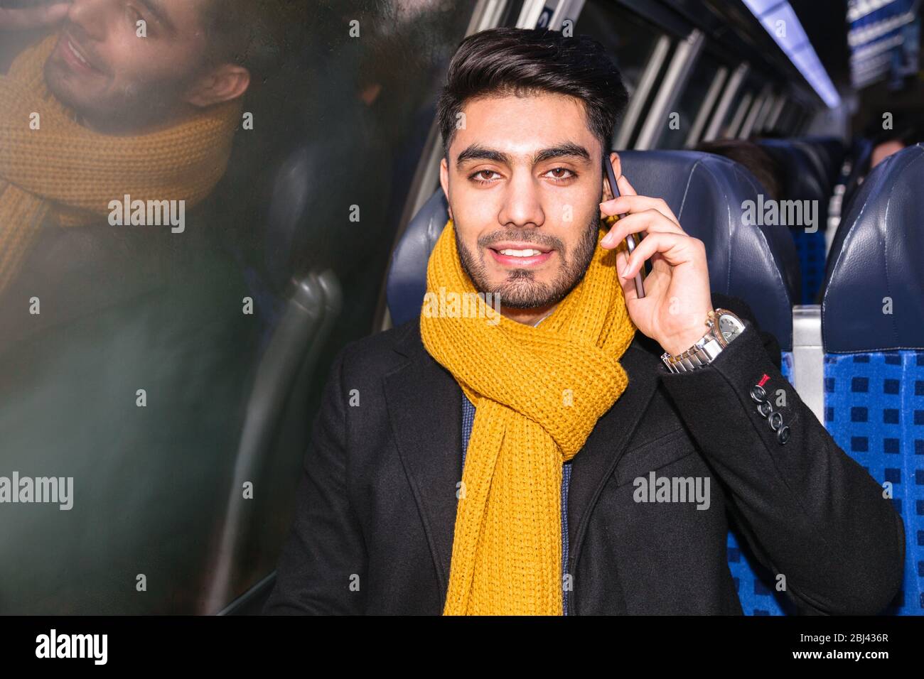 Businessman commuting to work on train using phone Stock Photo