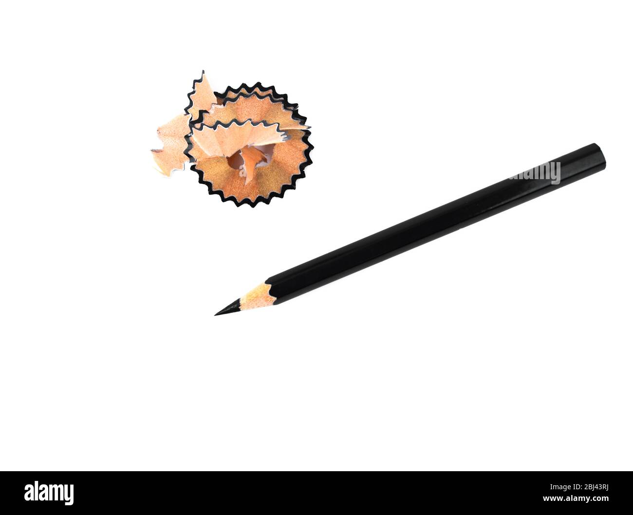 Pencil shavings placed beside a black color wood pencil crayon on a white isolated background Stock Photo