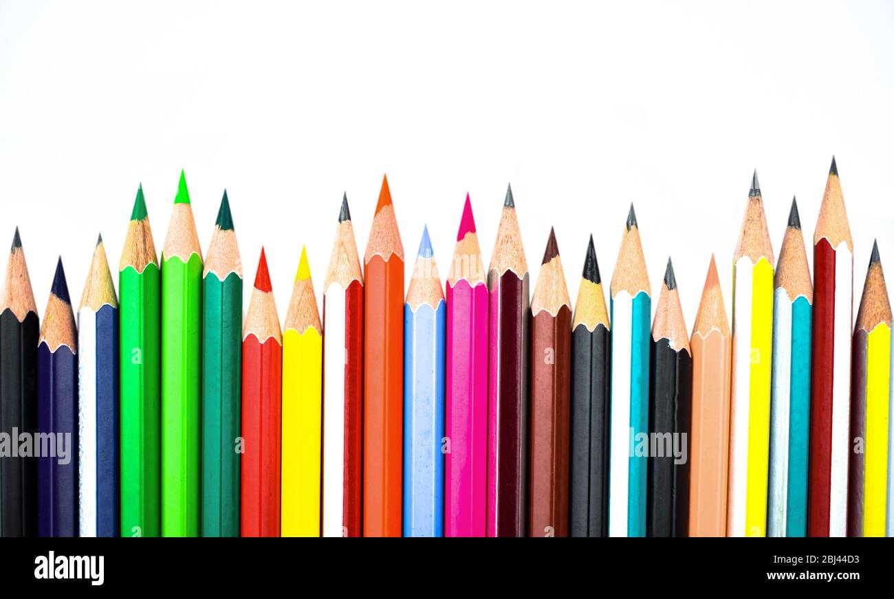 Various colored wooden pencil crayons placed in a row in front of a white isolated background