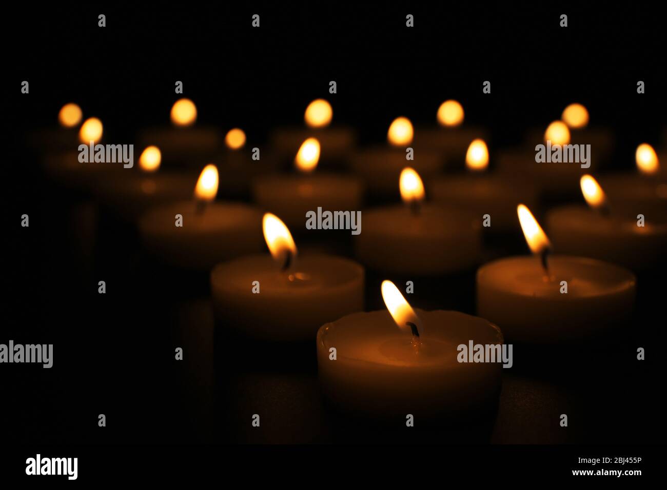 Alight candles in a row on black background Stock Photo - Alamy