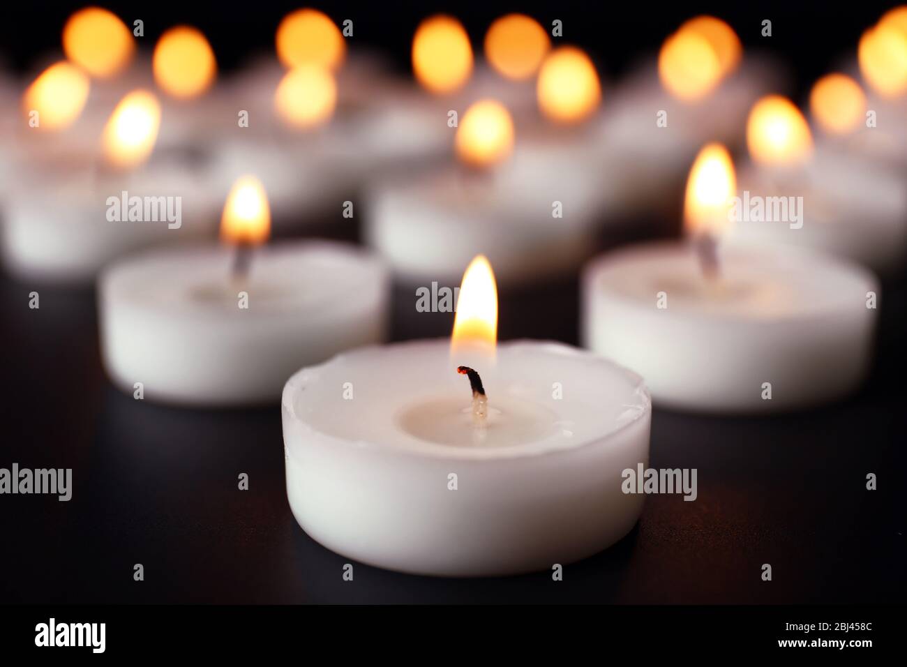 Alight candles in a row on black background, blurred Stock Photo - Alamy