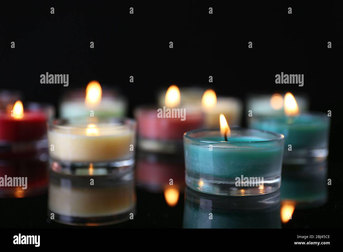 Colourful alight candles in a row on black background, blurred Stock ...