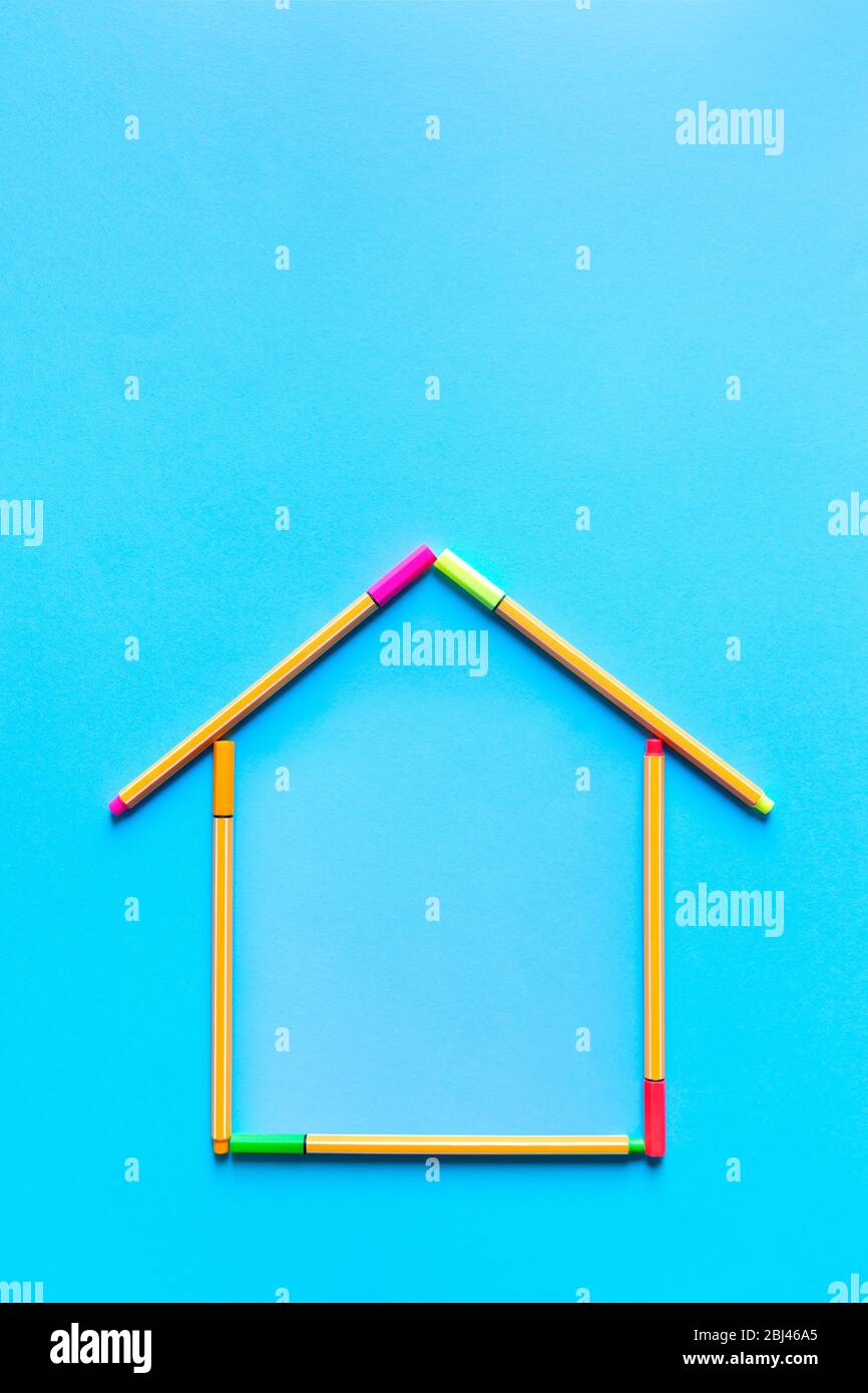 Top view of fluorescent marker pens forming a drawing of a house on pastel blue background, space for text. Housing concept. Stock Photo