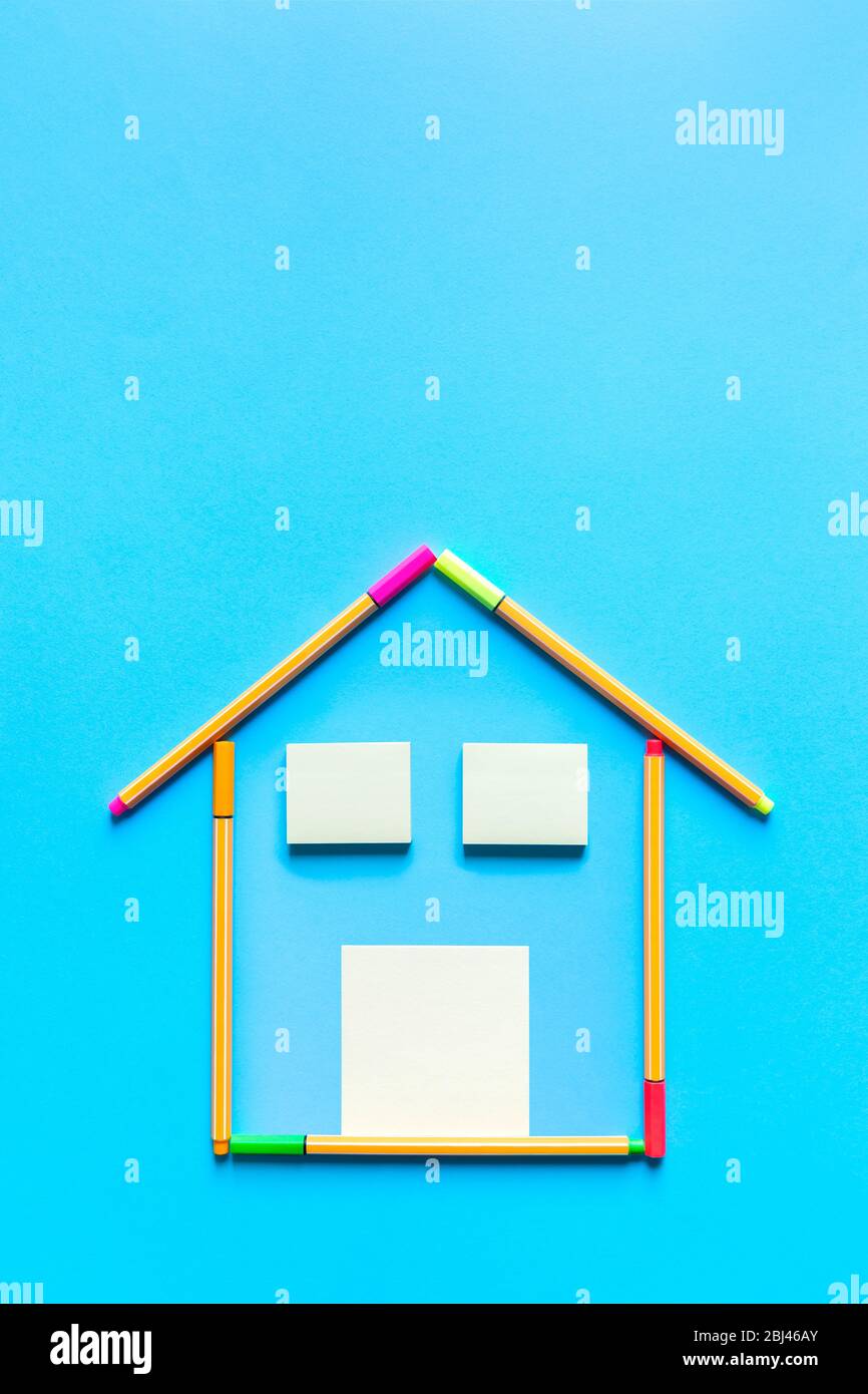 Top view of sticky notes and fluorescent marker pens forming a drawing of a house on pastel blue background, space for text. Housing concept. Stock Photo