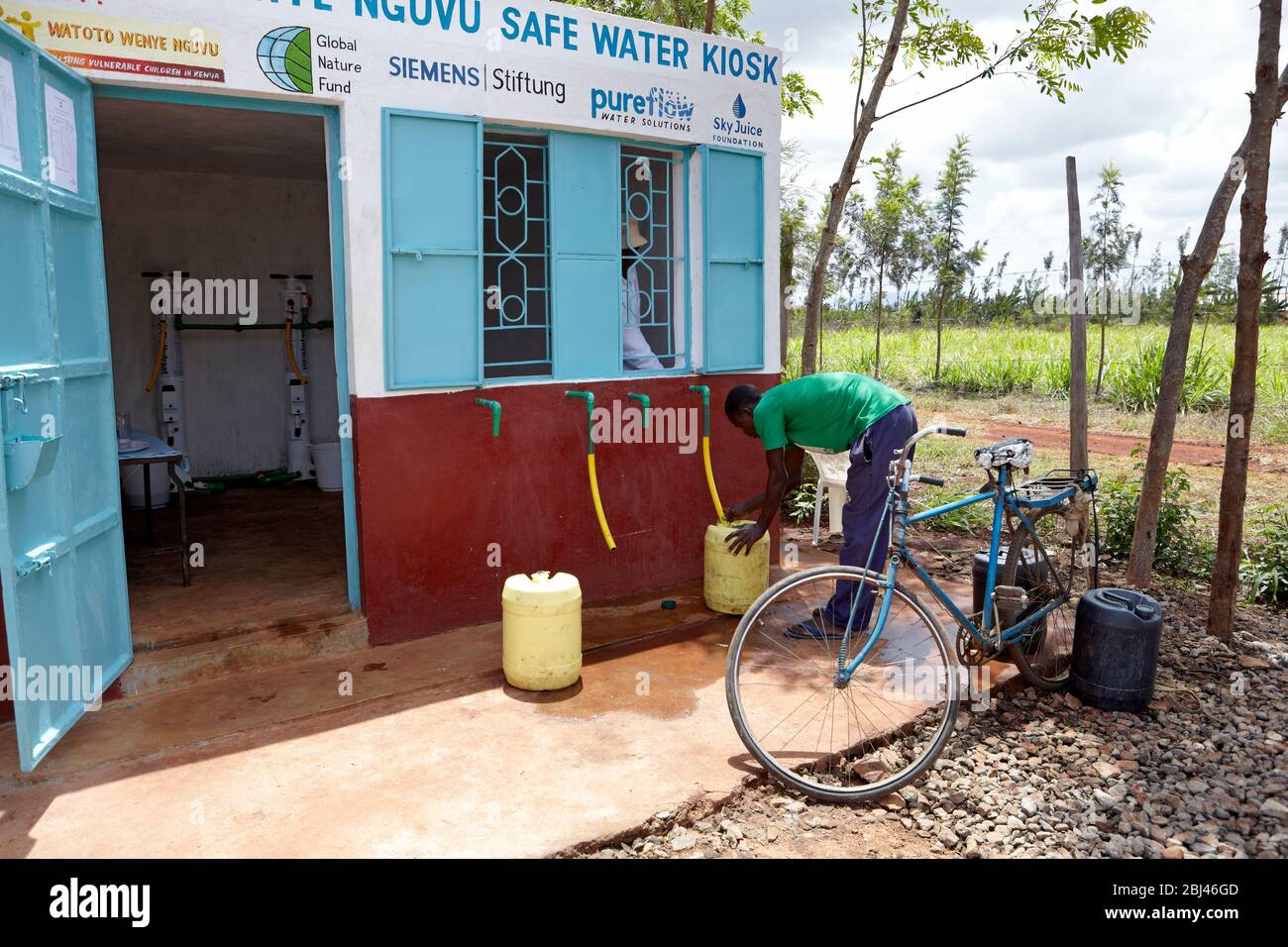 Young man carries a filled water canister from the waterhole in Mungetho, north of Naurobi to his bicycle. Stock Photo