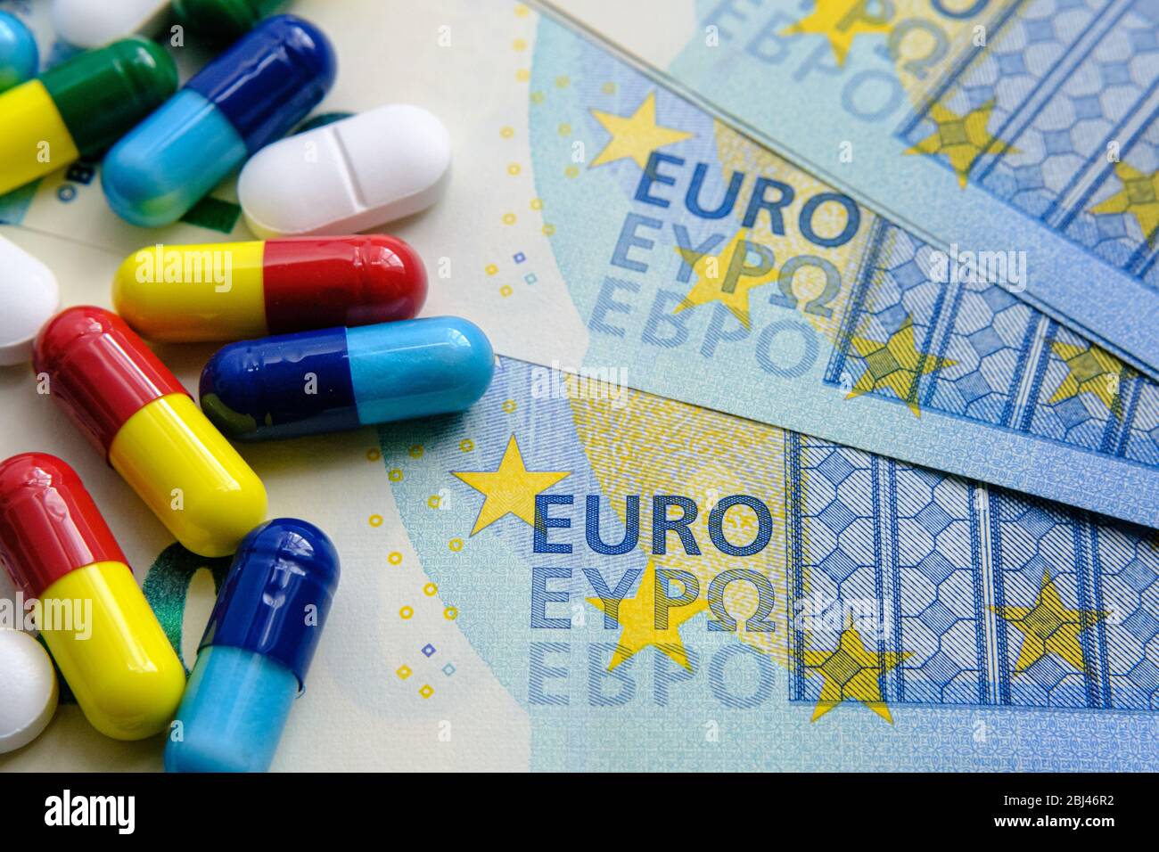 Pile of of different colouful pills placed next to 20 euro banknotes. Illustrative for cost of medical bills, health insurance and other subjects. Mac Stock Photo