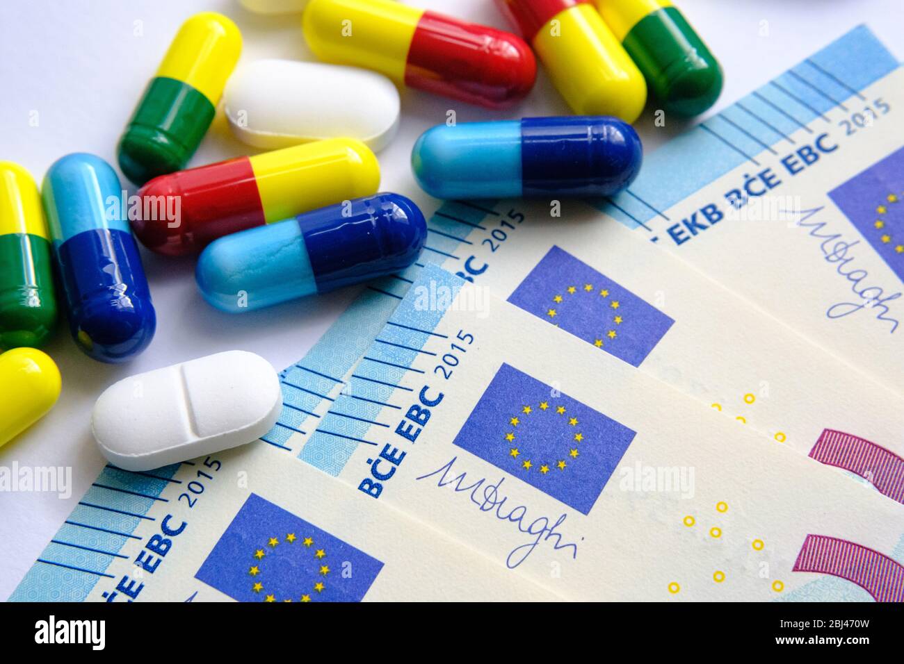 Pile of of different colouful pills placed next to 20 euro banknotes. Illustrative for cost of medical bills, health insurance and other subjects. Mac Stock Photo