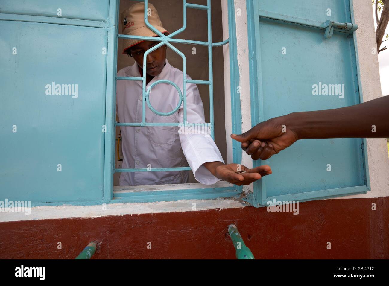 David fills its water cans at the water place in Mungetho, north of Nairobi and pays the water. Stock Photo