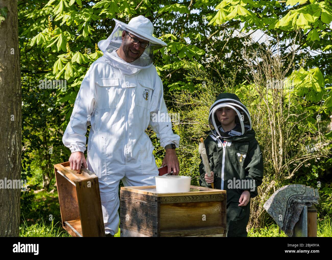 Camptoun, East Lothian, Scotland, United Kingdom. 28th Apr, 2020. A community in lockdown: residents in a small rural community show what life in lockdown is like for them. Pictured: Shane and his son Charlie, aged 9 years, are in their second year of keeping honey bees and hope to produce jars of honey this year. The hive contains around 20,000 bees Stock Photo