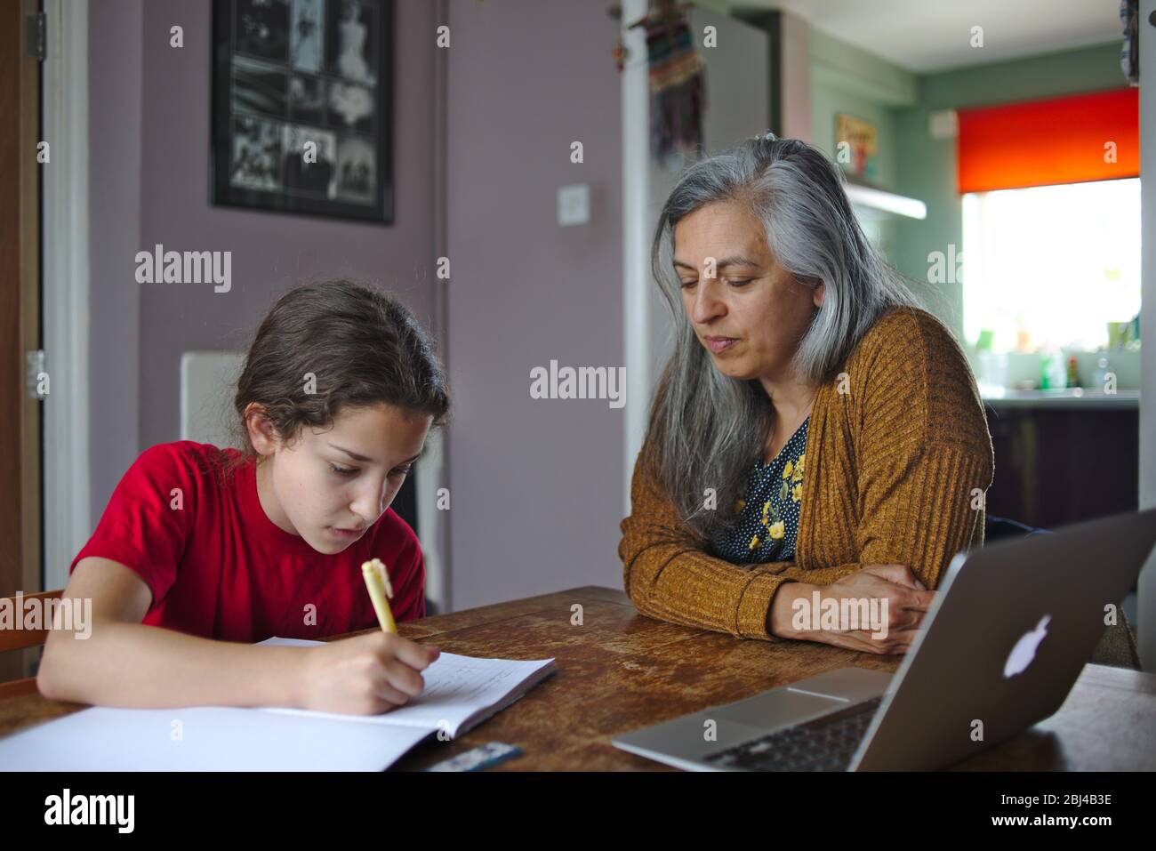 Parent helping child with school work at home during coronavirus lockdown. April 2020 UK Stock Photo