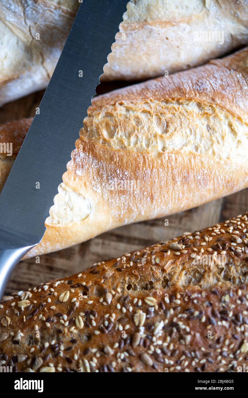 Selection of freshly baked baguettes with bread knife Stock Photo