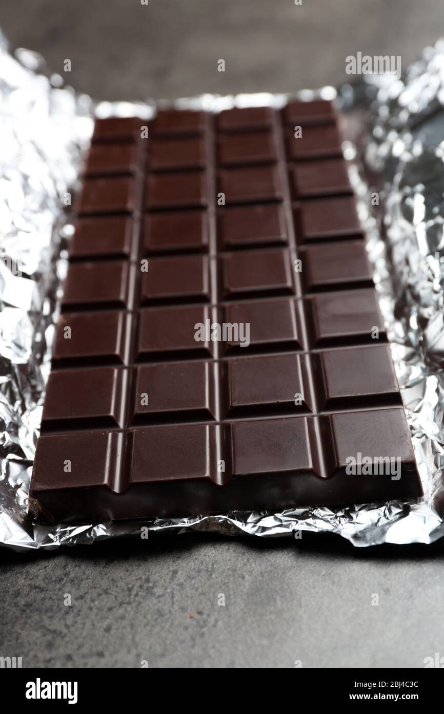 Chocolate bar in foil on gray background Stock Photo - Alamy