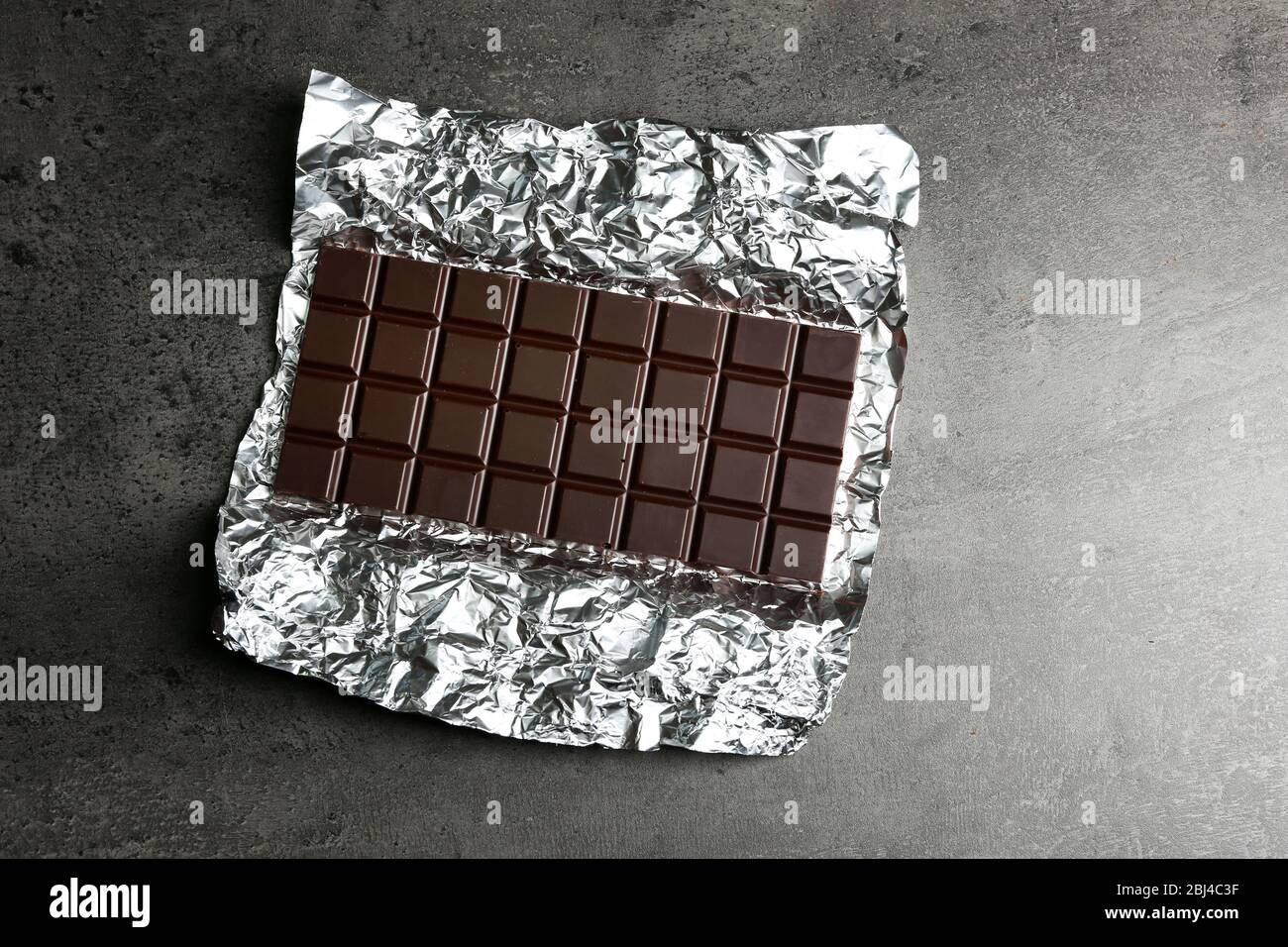 Chocolate bar in foil on gray background Stock Photo - Alamy