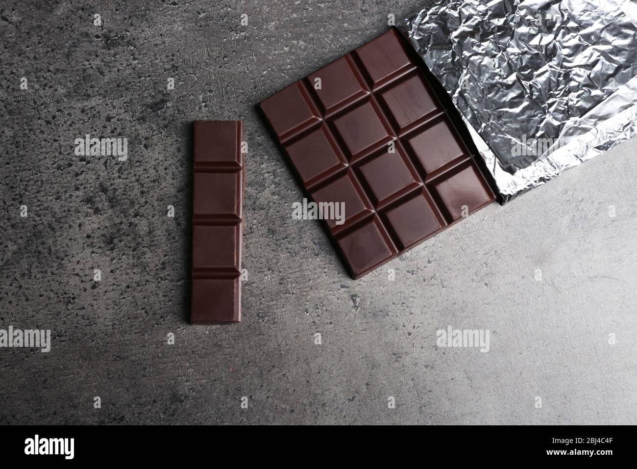 Chocolate bar in foil on gray background Stock Photo - Alamy
