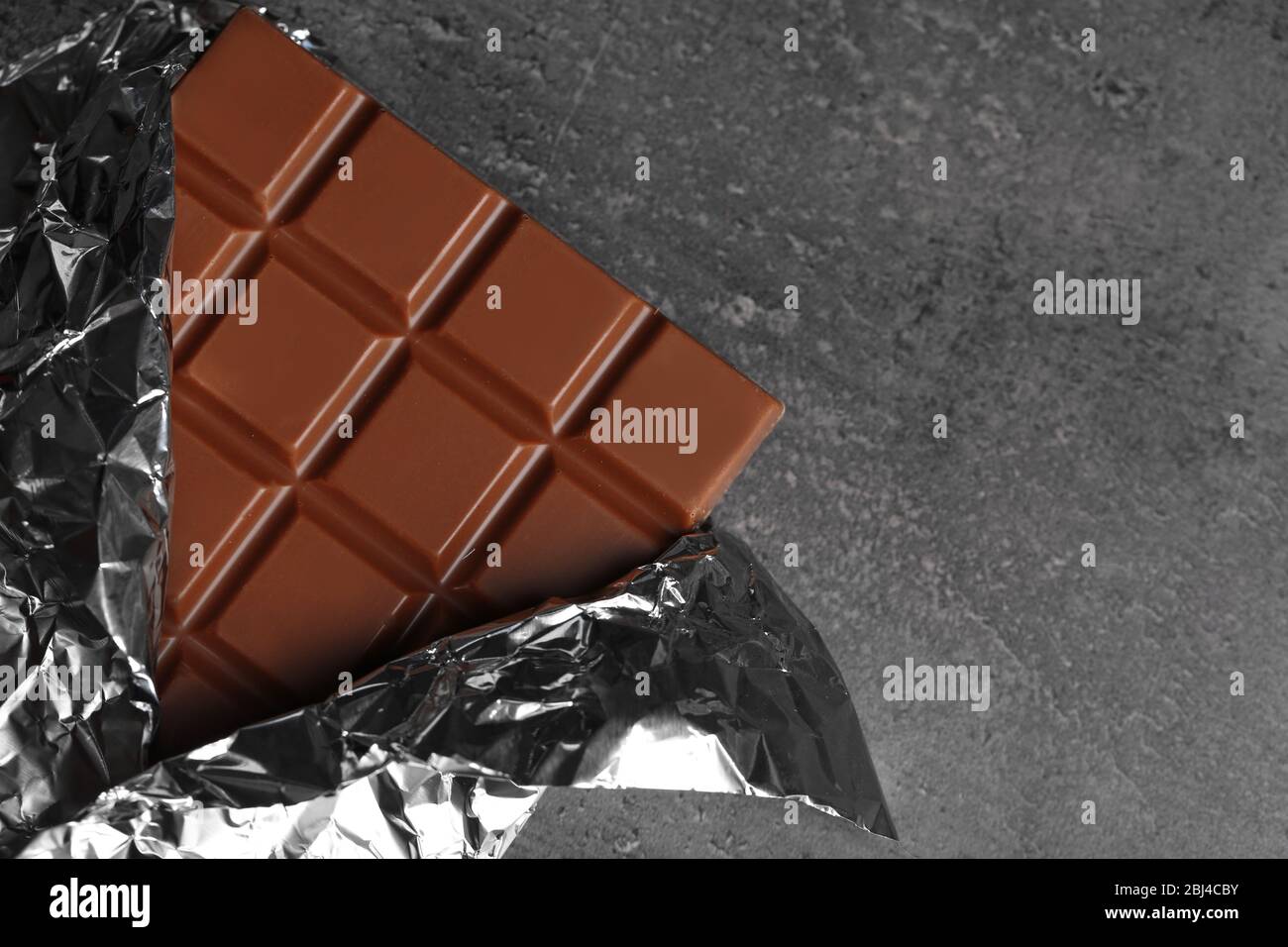 Chocolate bar in foil on gray background Stock Photo - Alamy