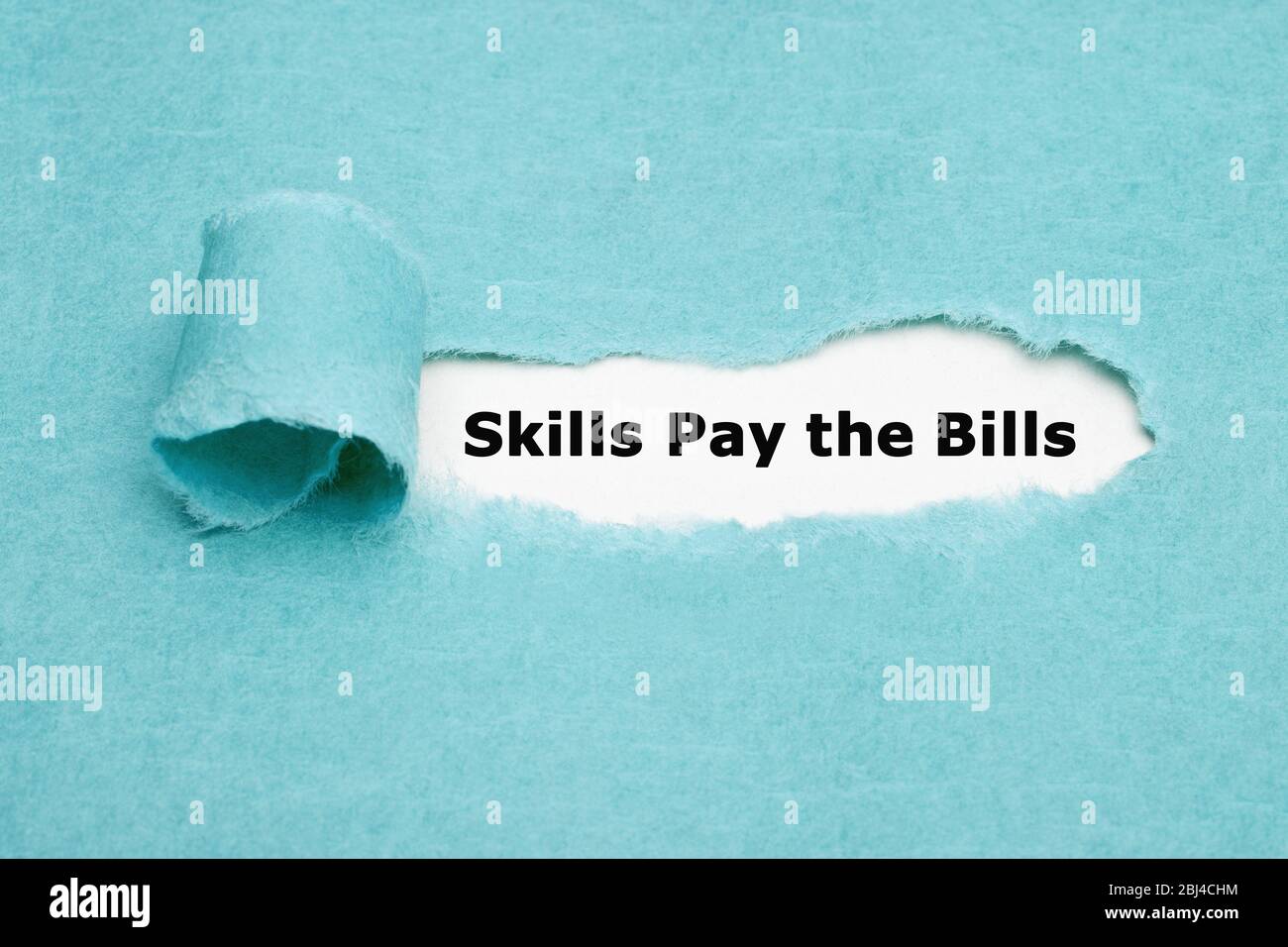 Printed text Skills Pay the Bills appearing behind torn blue paper. Stock Photo