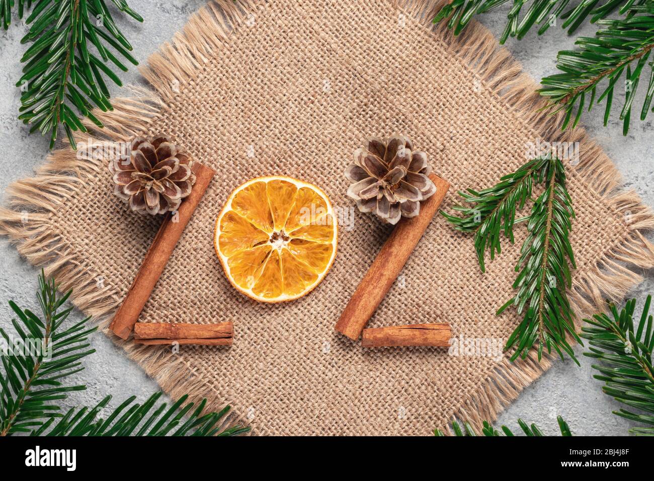 Christmas celebration with zero waste concept. Christmas eco friendly decoration. Figures 2021 from natural materials on burlap on a gray table. Stock Photo