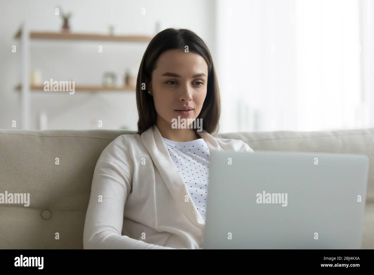 Caucasian young woman using laptop relaxing at home Stock Photo - Alamy