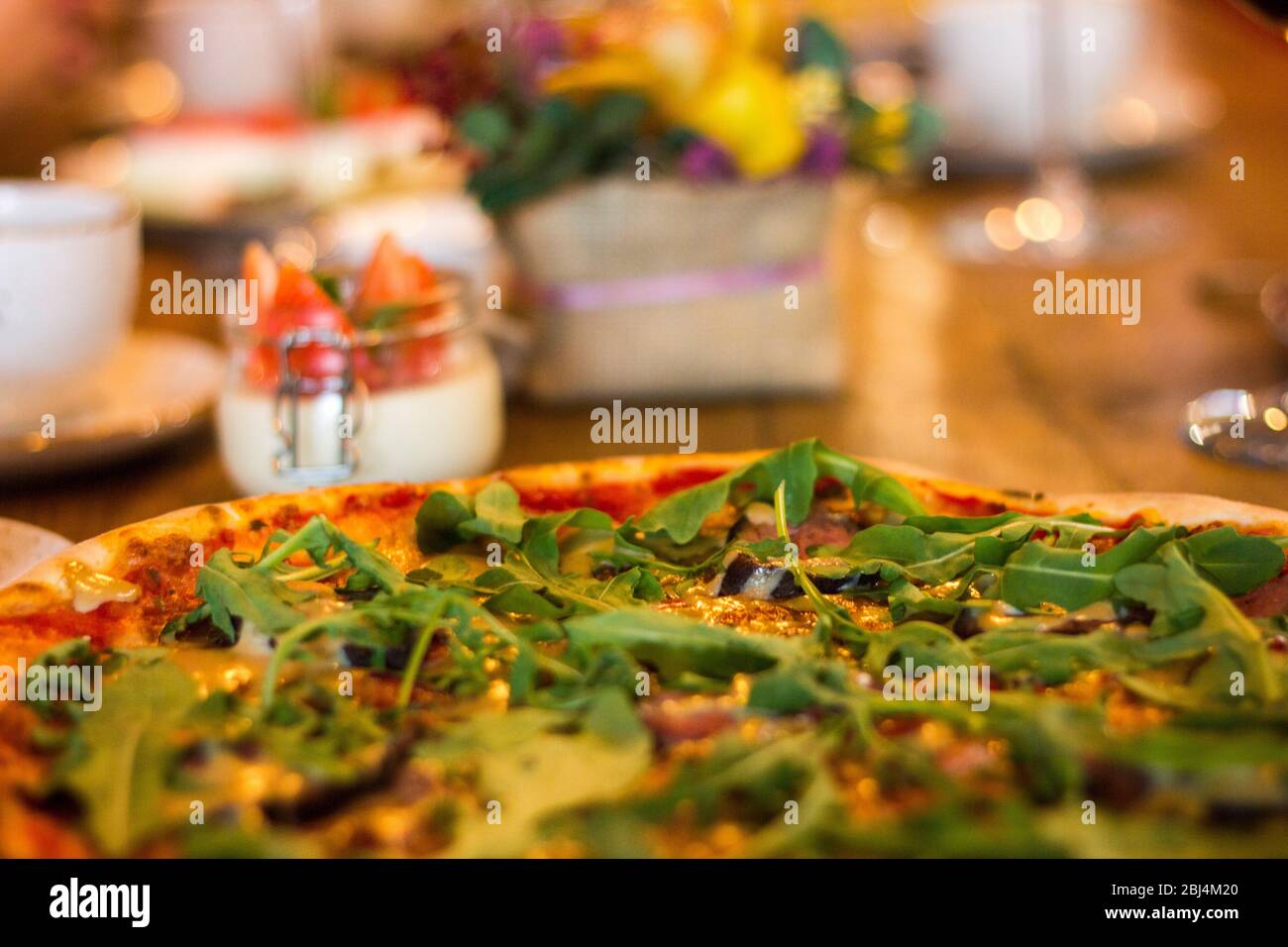 Pizza with meat and cheese decorated with greens on a plate Stock Photo