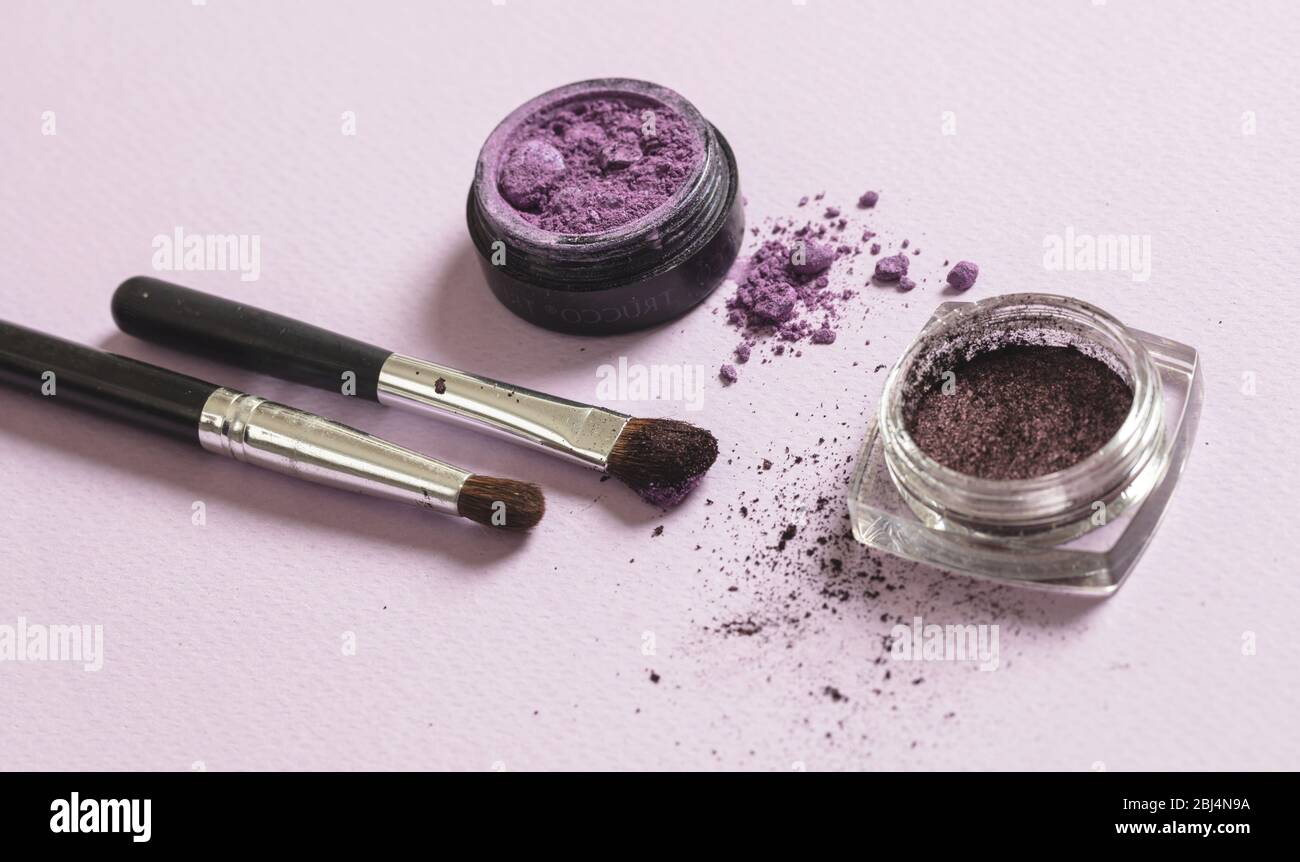 Eyeshadow purple color and brushes against pink background, closeup view. Professional tools for make up, beauty salon, cosmetics concept Stock Photo