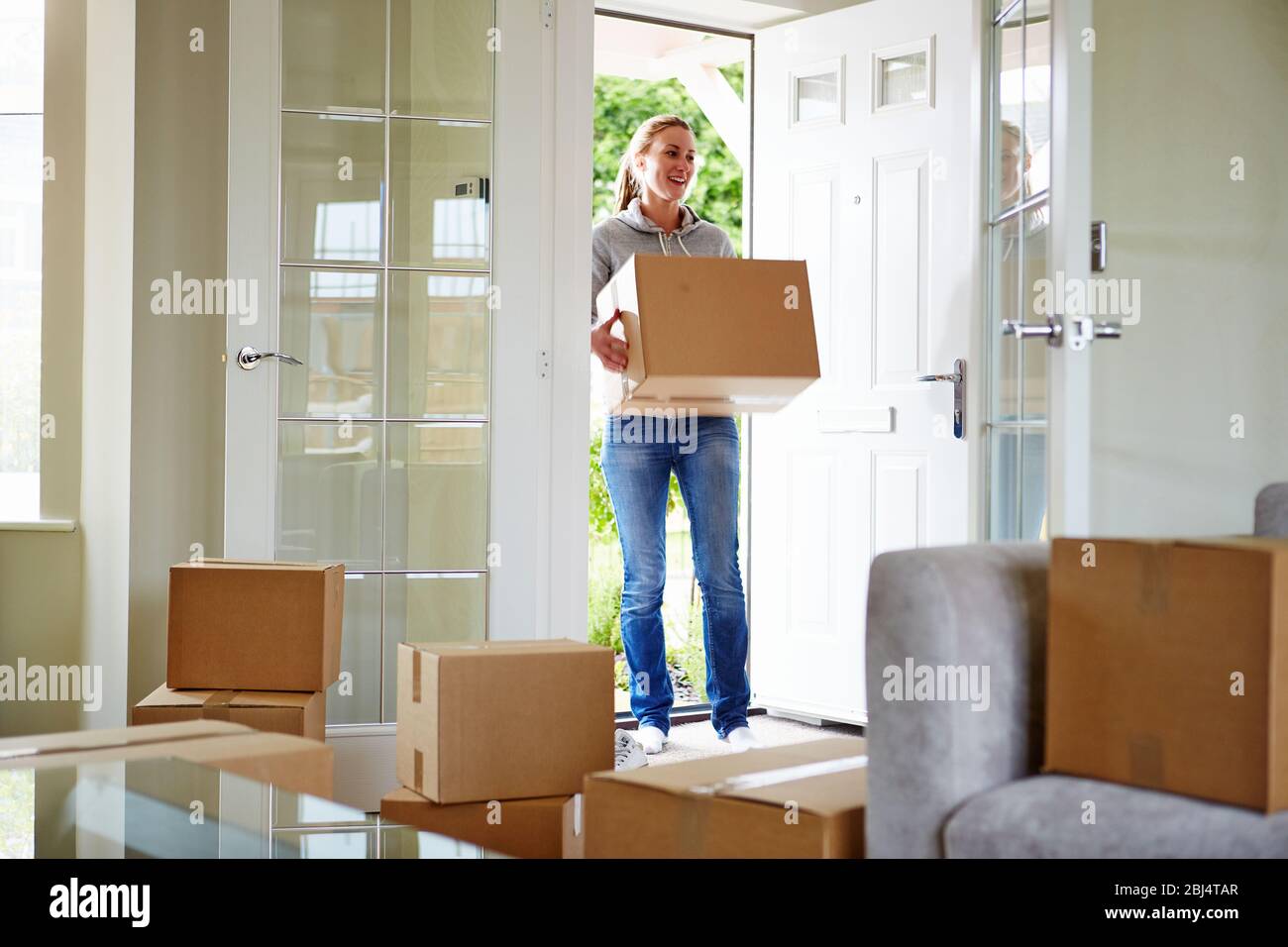 Young woman moving into new apartment holding cardboard boxes with belongings Stock Photo