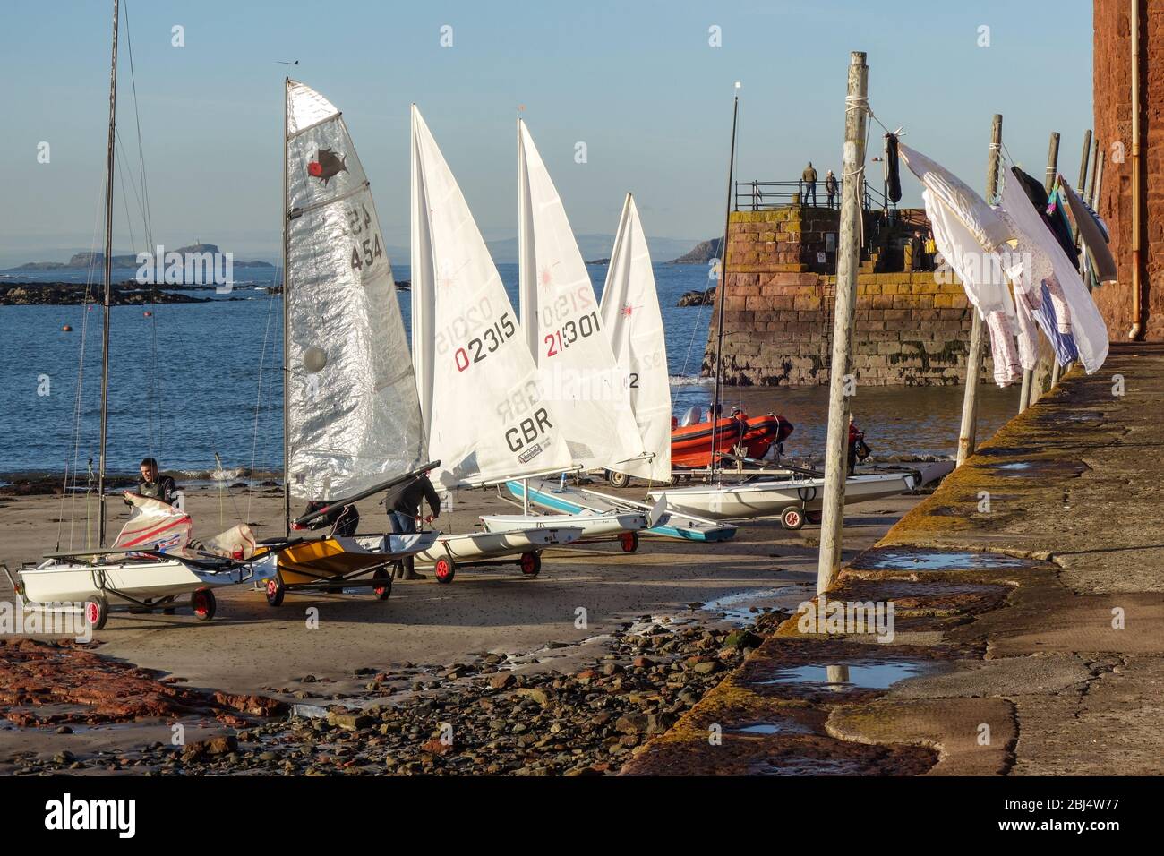 Sailing Dinghies, preparing for club racing, and washing line on Low Quay, The Harbour, North Berwick Stock Photo