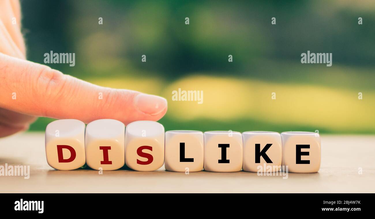 Hand turns dice and changes the expression "dislike" to "like". Stock Photo