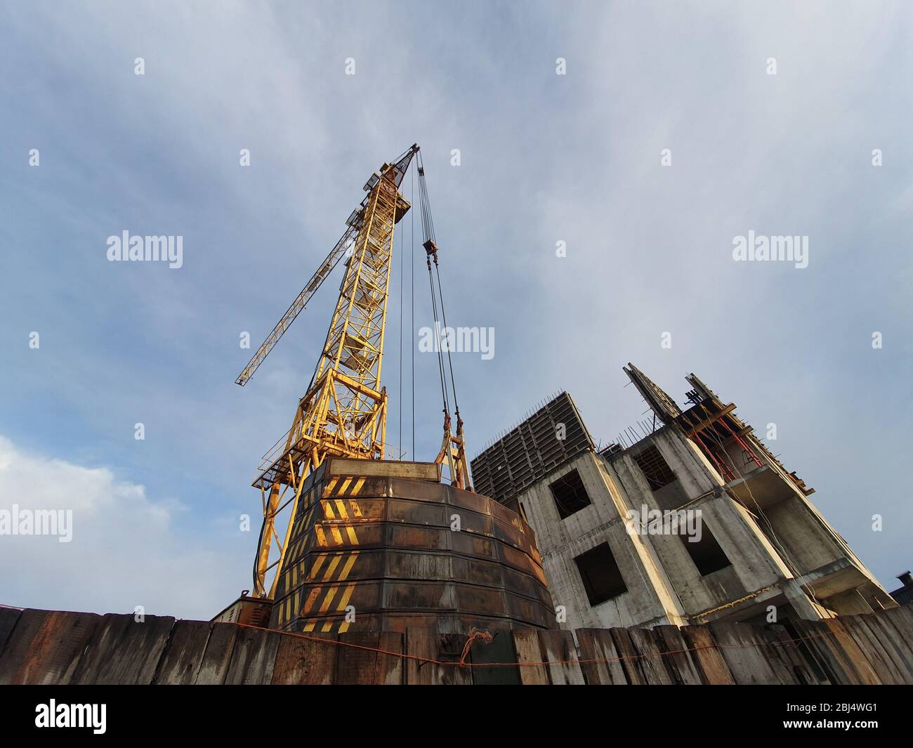 The construction of a monolithic residential building. A large crane stands next to a multi-storey building, which has not yet been completed. Stock Photo