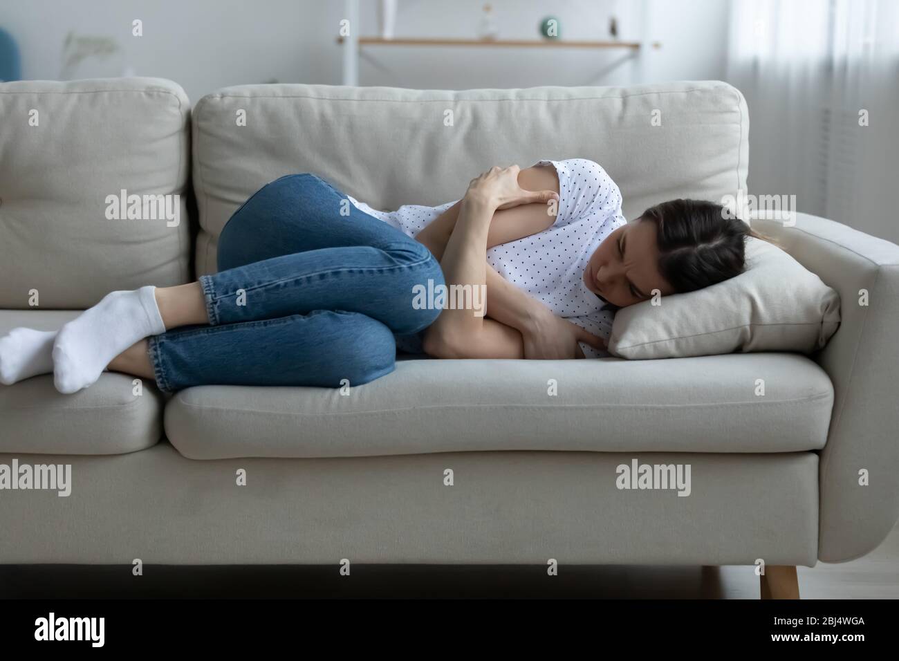 Upset young woman lying on couch feeling depressed Stock Photo
