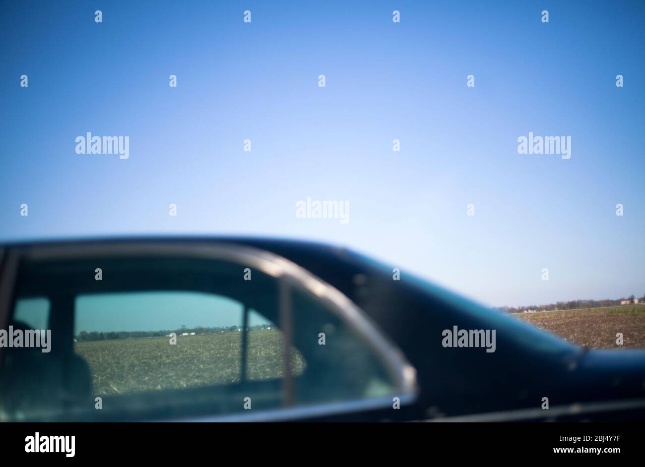View across a field somewhere in the mid-West of America with a car in the foreground. Stock Photo