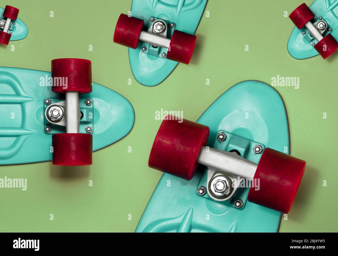 Turquoise Skateboards on green background, top view. Concept of sport lifestyle, culture, leisure, hobby, alternative transport Stock Photo