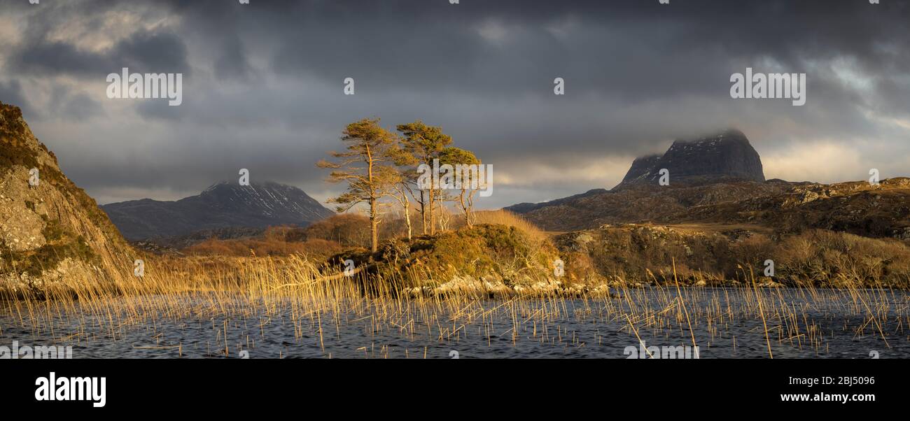 Fleeting light shining on Loch Druim Suardalain with Canisp and Suilven in the background. Stock Photo