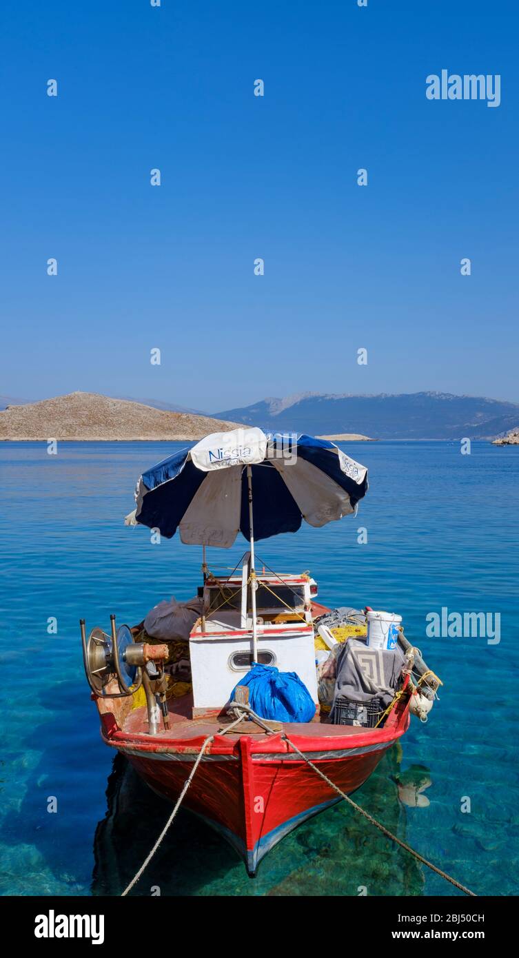 A small red fishing boat with a blue and white parasol. Stock Photo