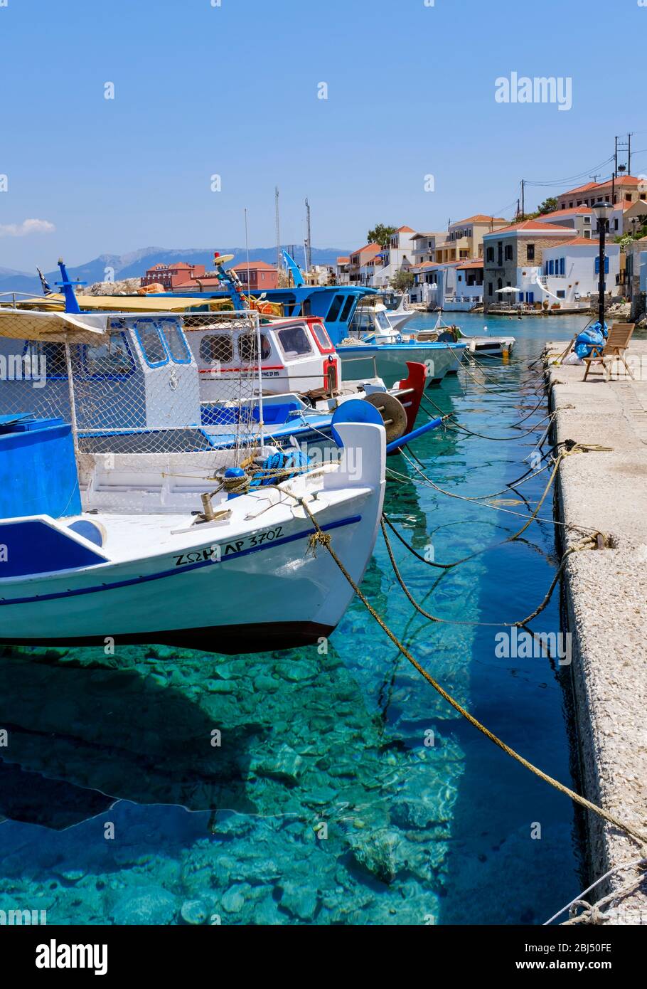 Boats in a row in the clear waters of Halki harbour. Stock Photo