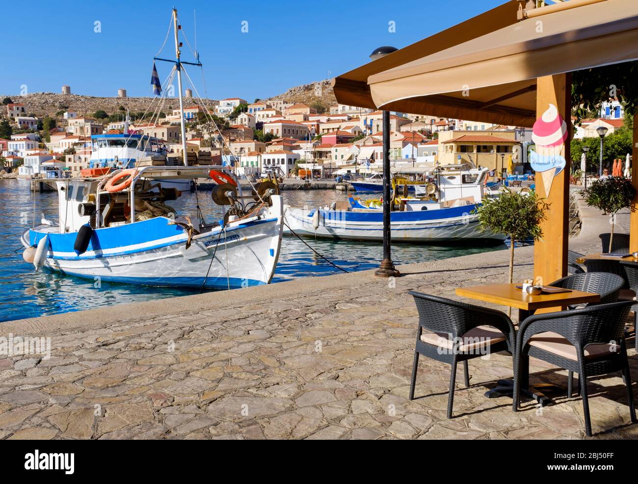 Halki cafe bar next to the fishing boats in the harbour. Stock Photo
