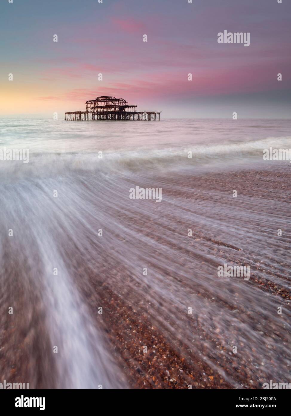 Pink sky over the old west pier at sunrise. Stock Photo