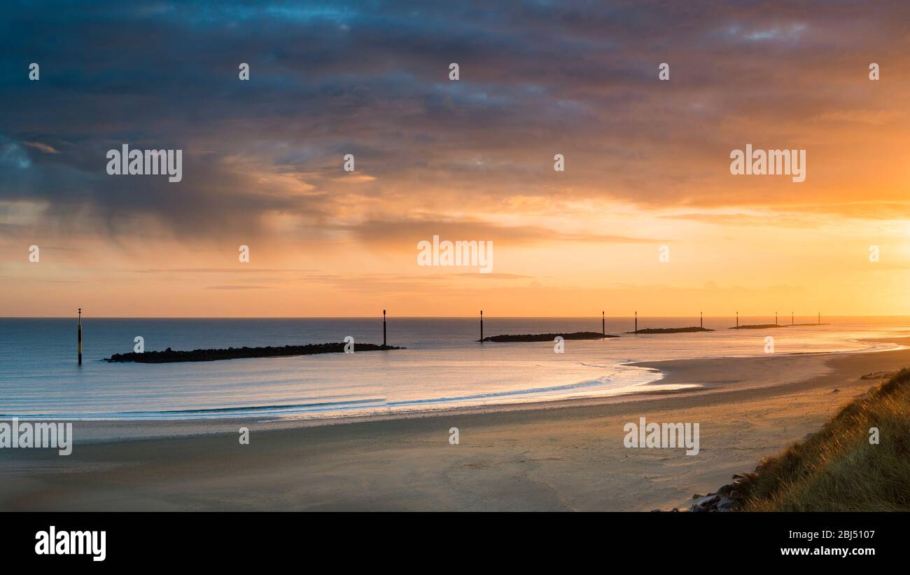 A colourful sunrise over Sea Palling beach sea defenses. Stock Photo