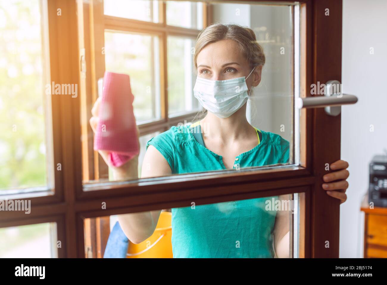 Woman cleaning windows during covid-19 lockdown Stock Photo