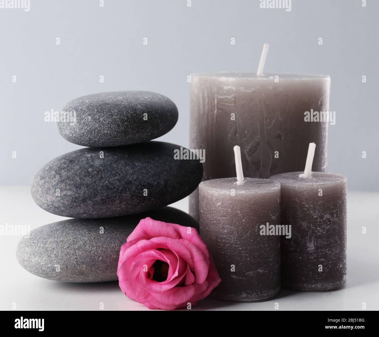 Aroma candles with pebbles and flower isolated on white background